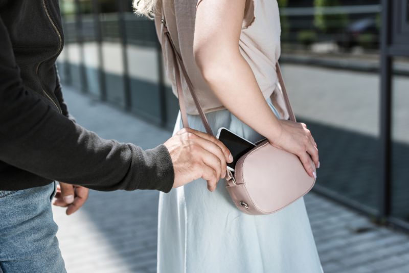 Man pickpocketing a phone from a womans purse
