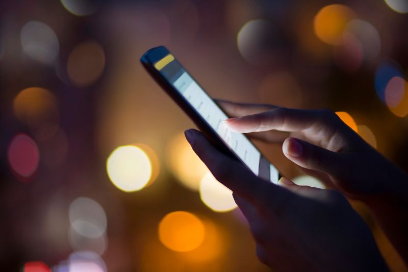 Person holding a phone in the dark with lights in the background in Barcelona Spain