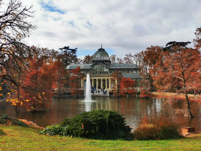 Retiro Park in Madrid - a lake with a fountain and a pretty building beyond it